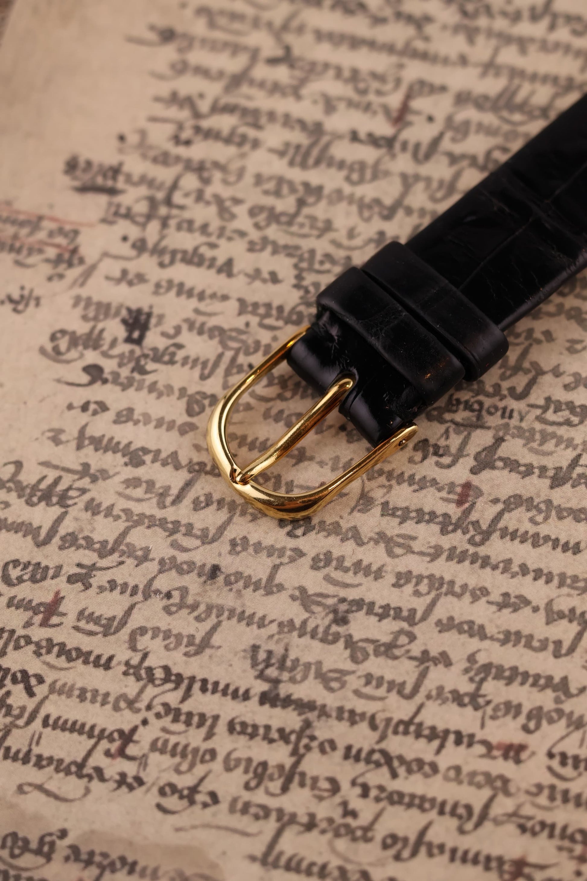 Original Audemars Piguet 18K yellow gold buckle on black leather strap, part of vintage skeleton watch ensemble