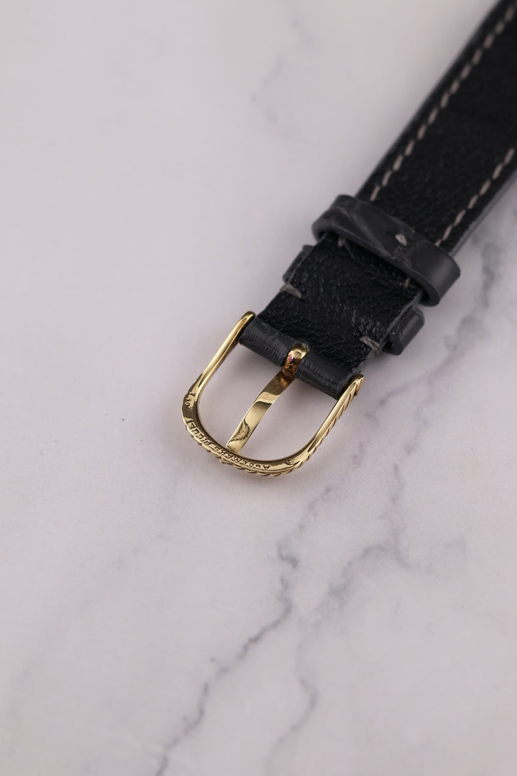 Underside of Audemars Piguet braided gold buckle attached to vintage leather strap