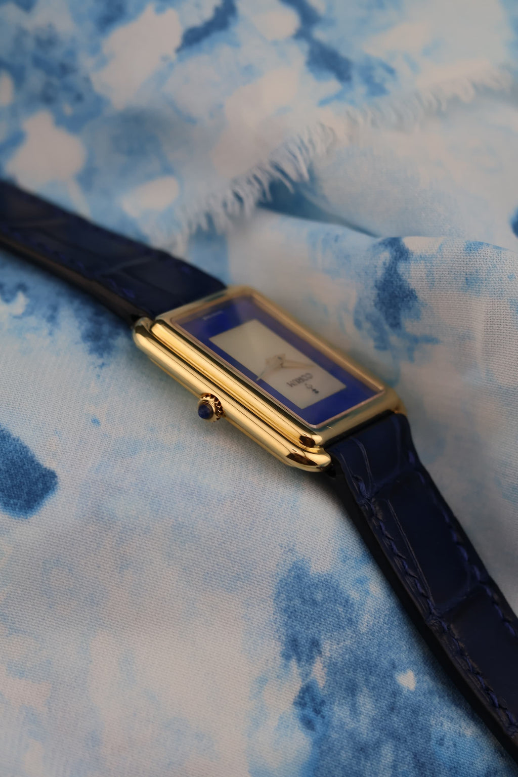 Sapphire cabochon crown on Corum 18K yellow gold tank watch, viewed from the side