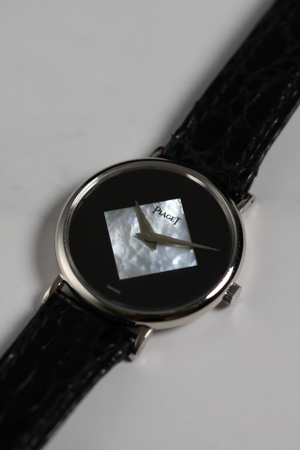 Close-up of the Piaget Ref. 922 dial featuring a diamond-shaped mother of pearl inlay set against a glossy black onyx background with silver dauphine hands.