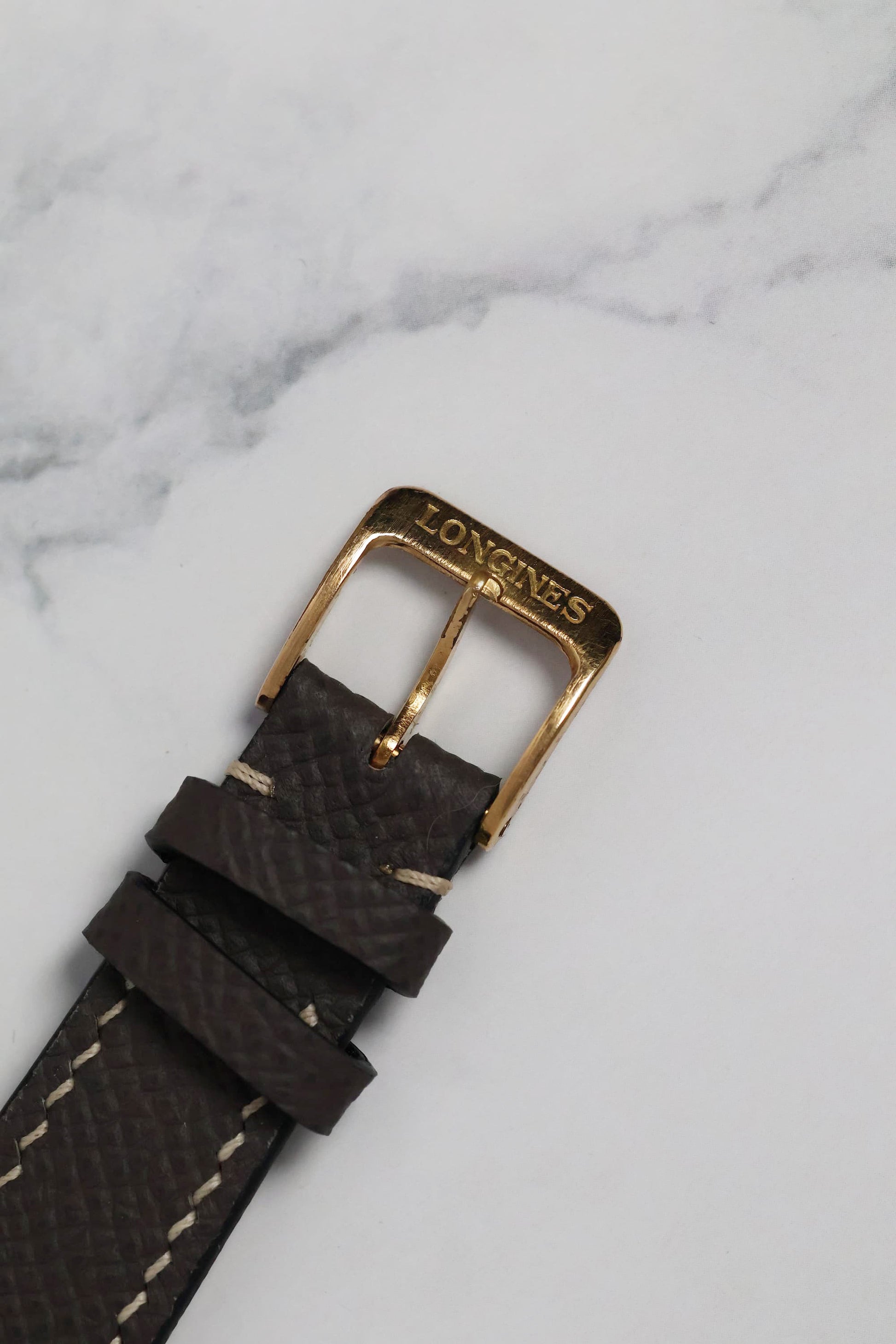 Close-up of the original vintage buckle that accompanies the watch, preserving its period-correct charm.