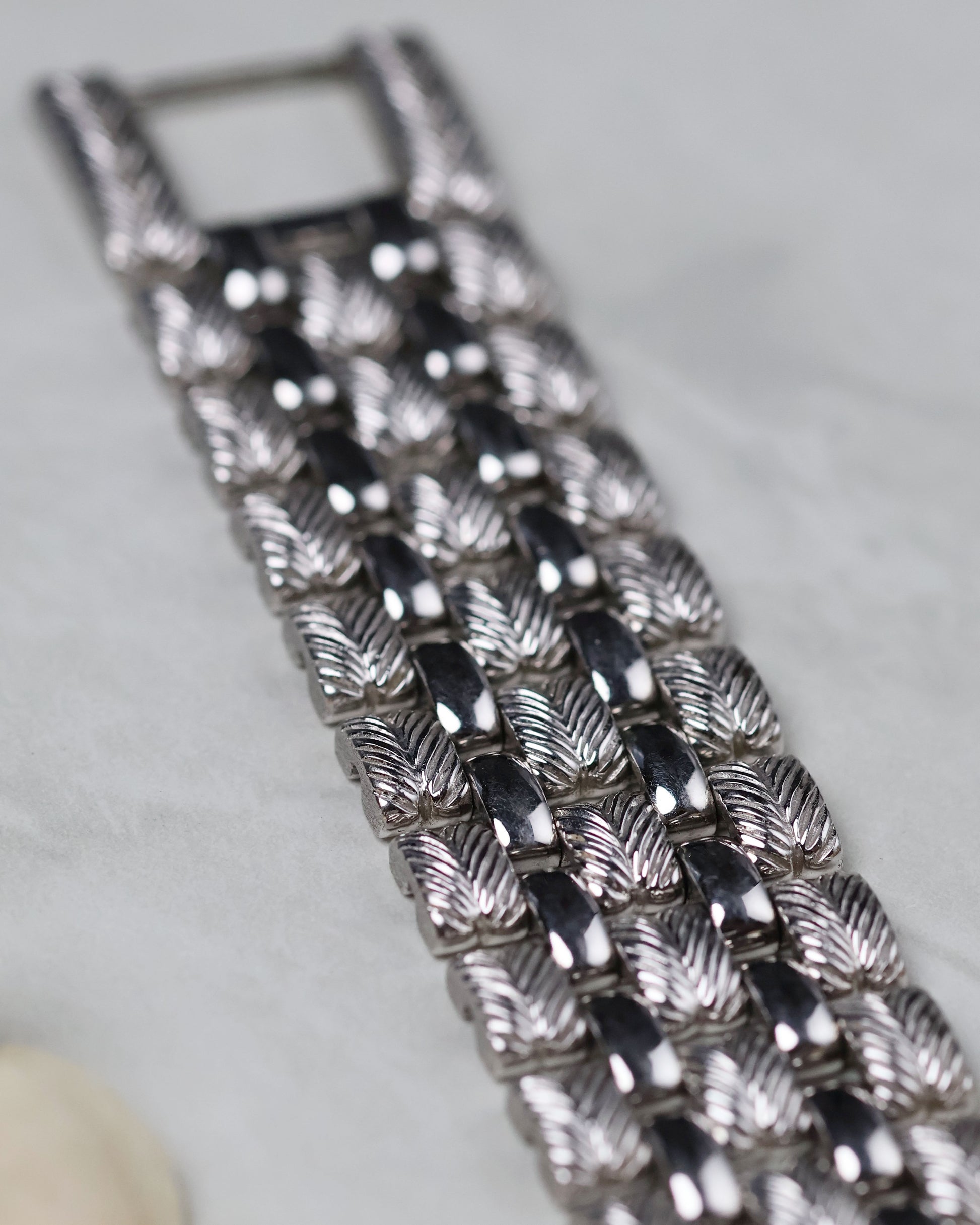 Detailed macro of the feather-pattern engraved white gold bracelet links.