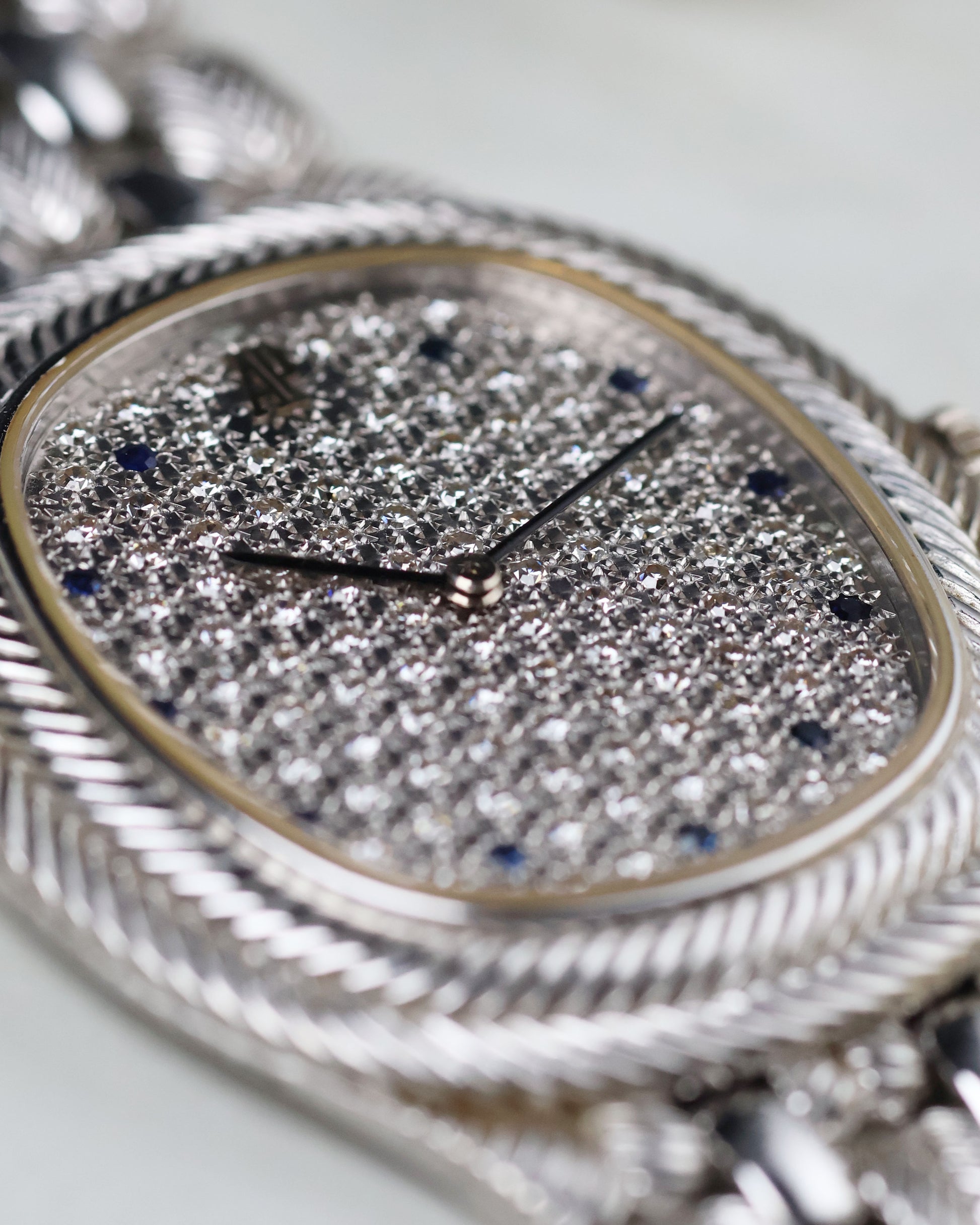 Macro of the diamond pavé dial with deep blue sapphire indexes capturing the light.