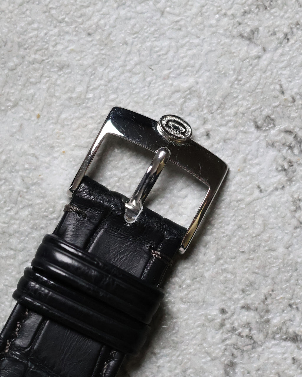 Top view of the Concord platinum buckle paired with black alligator strap.