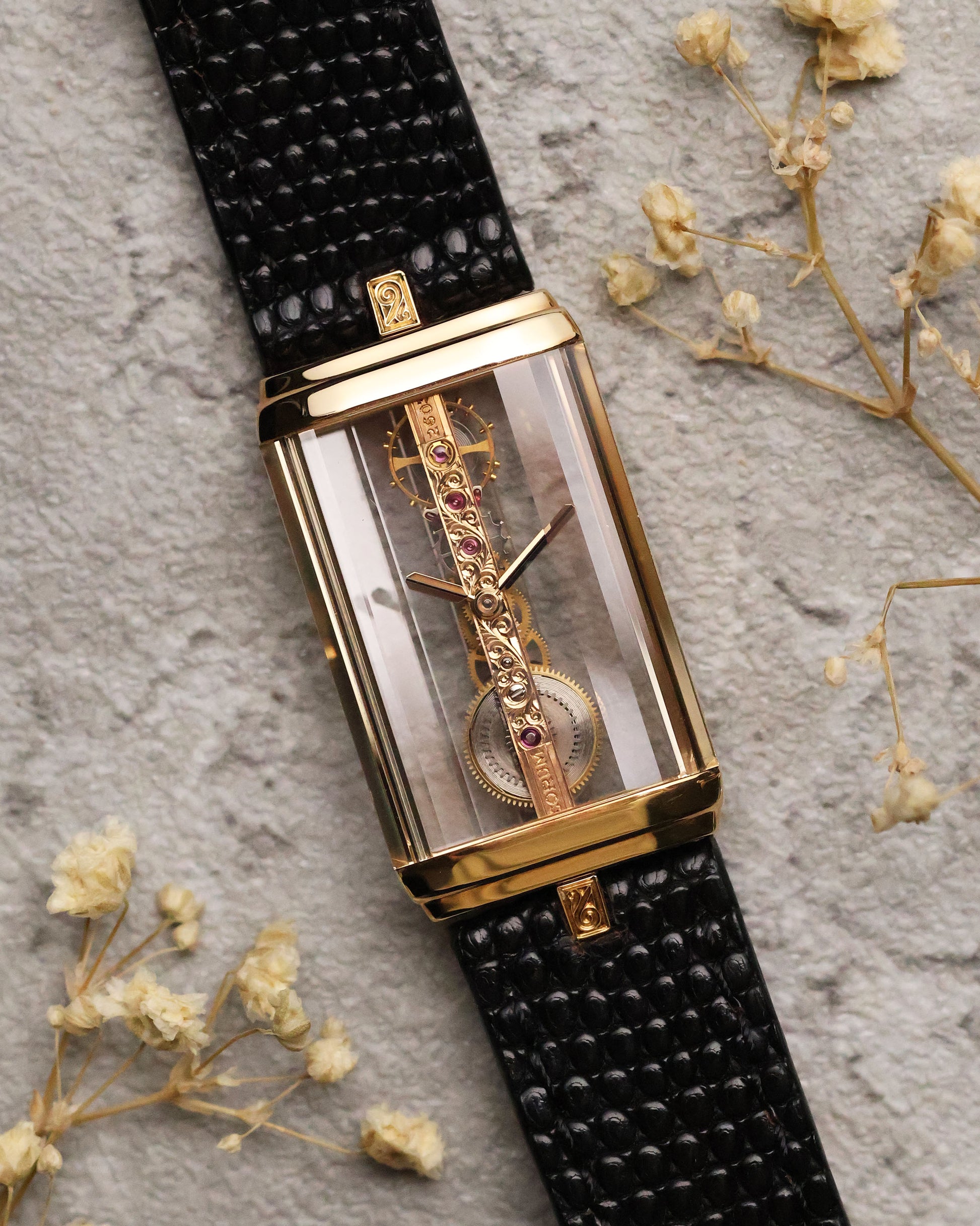 Full view of the Corum Golden Bridge 13150 on black textured leather strap, showcasing the rectangular 18k yellow gold case with transparent sapphire sides and the linear skeletonized movement visible through the front.