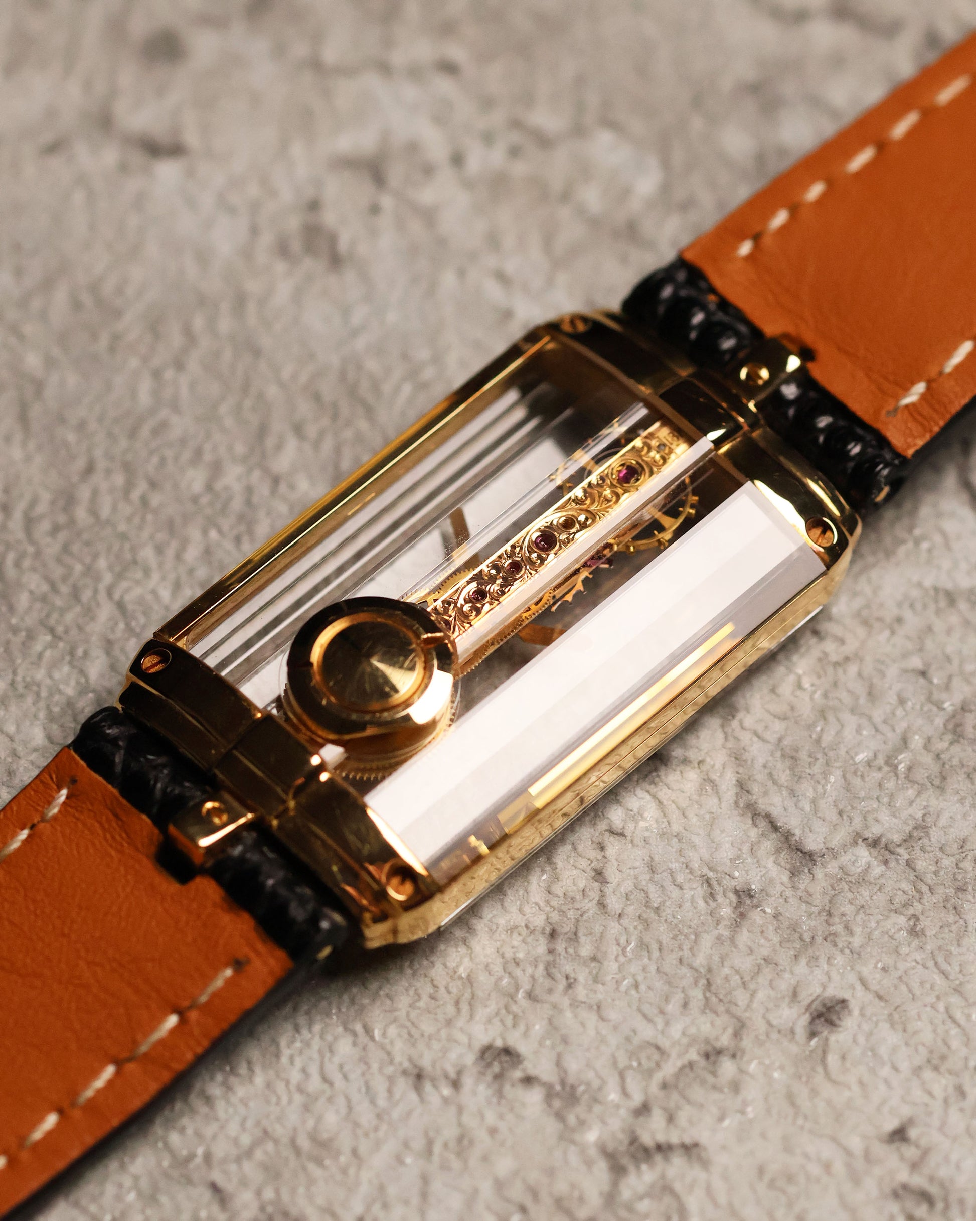 Low-angle caseback shot of the Corum Golden Bridge 13150, highlighting the back-mounted crown and gold screws securing the sapphire crystal structure.
