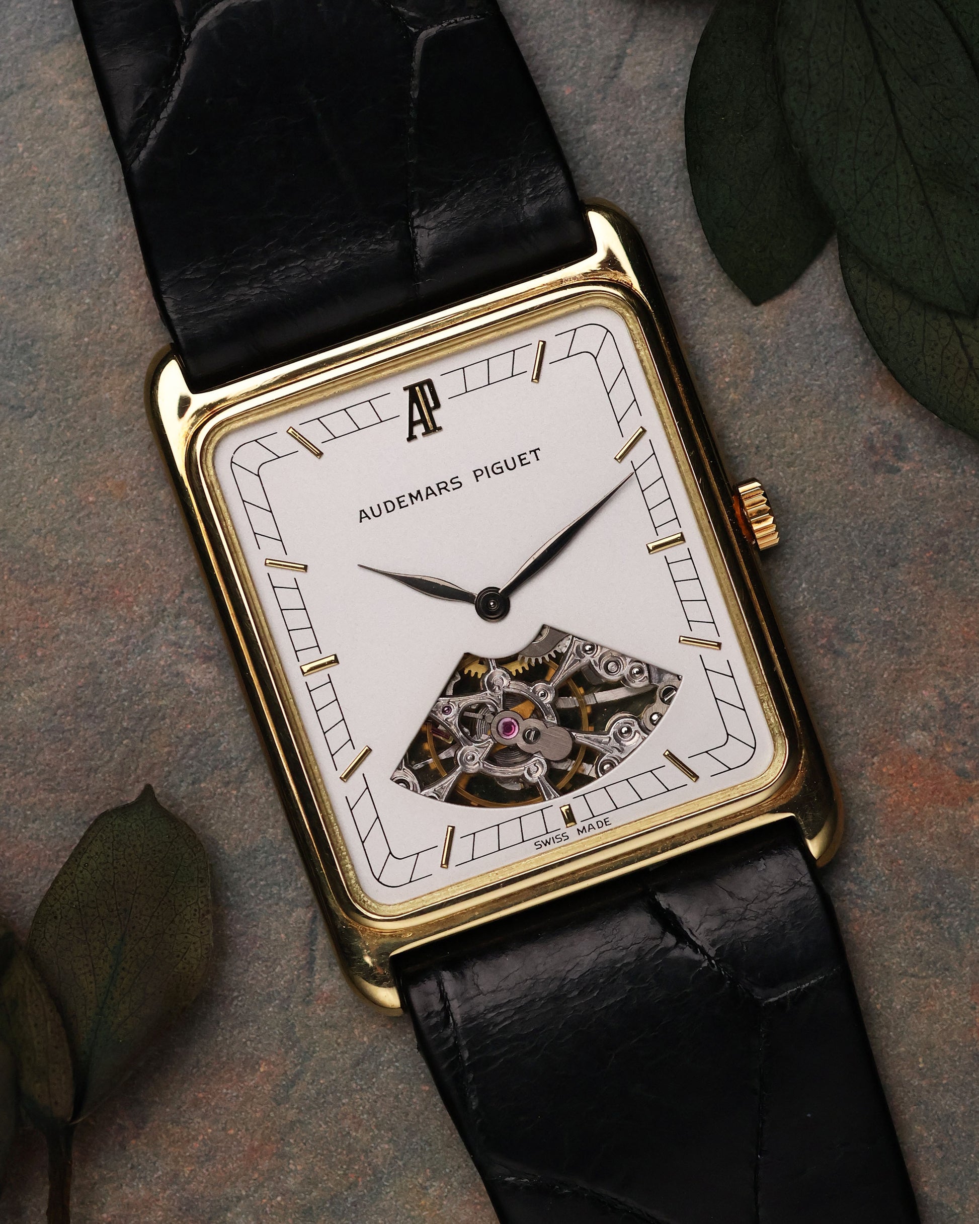 Flat lay of Audemars Piguet Skeleton Aperture Tank with leaves background, showcasing dial and skeleton aperture.