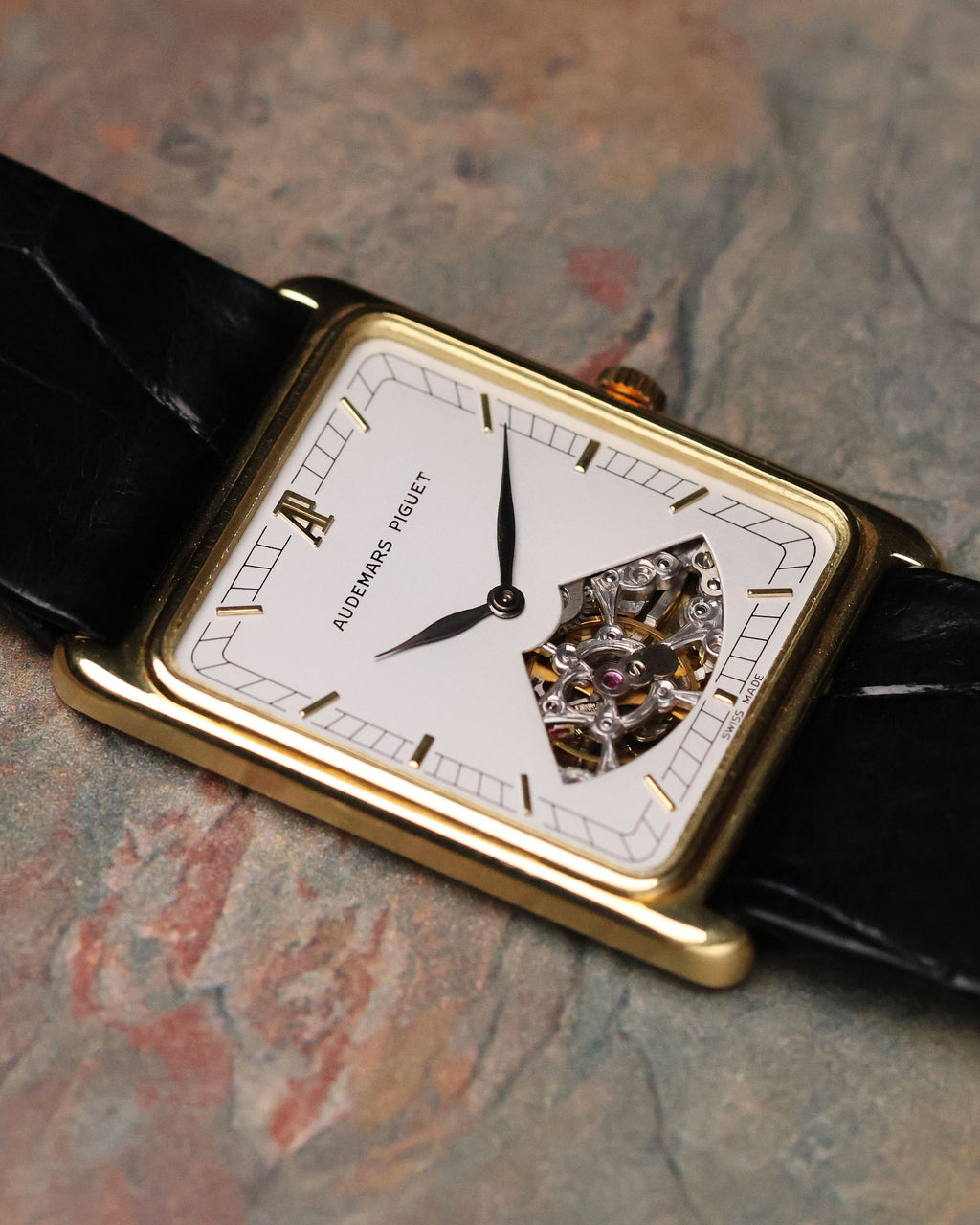 Audemars Piguet Skeleton Aperture Tank watch – 18K yellow gold rectangular case with white dial and skeleton aperture revealing manual movement.