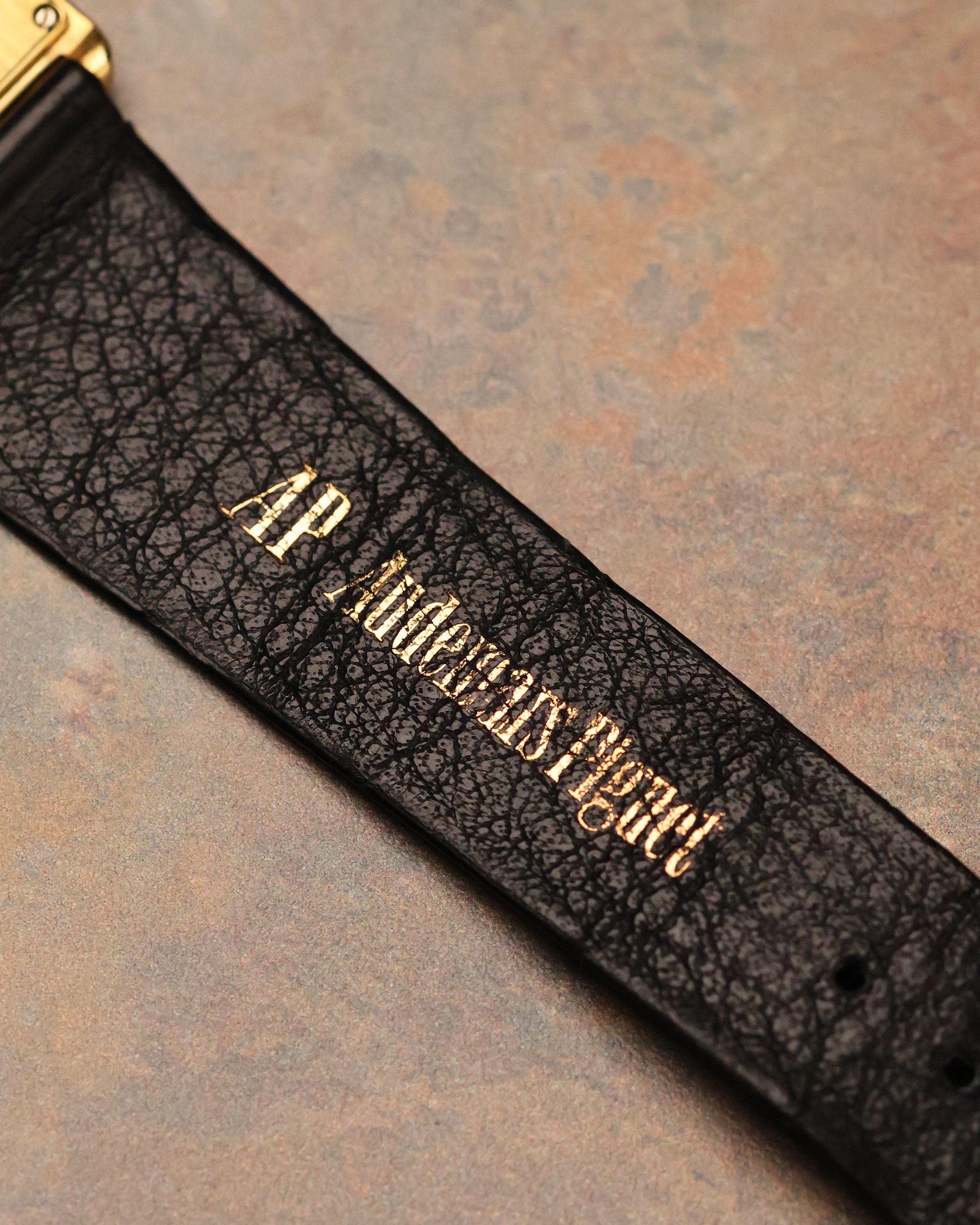 Macro detail of Audemars Piguet leather strap with gold-stamped brand signature.