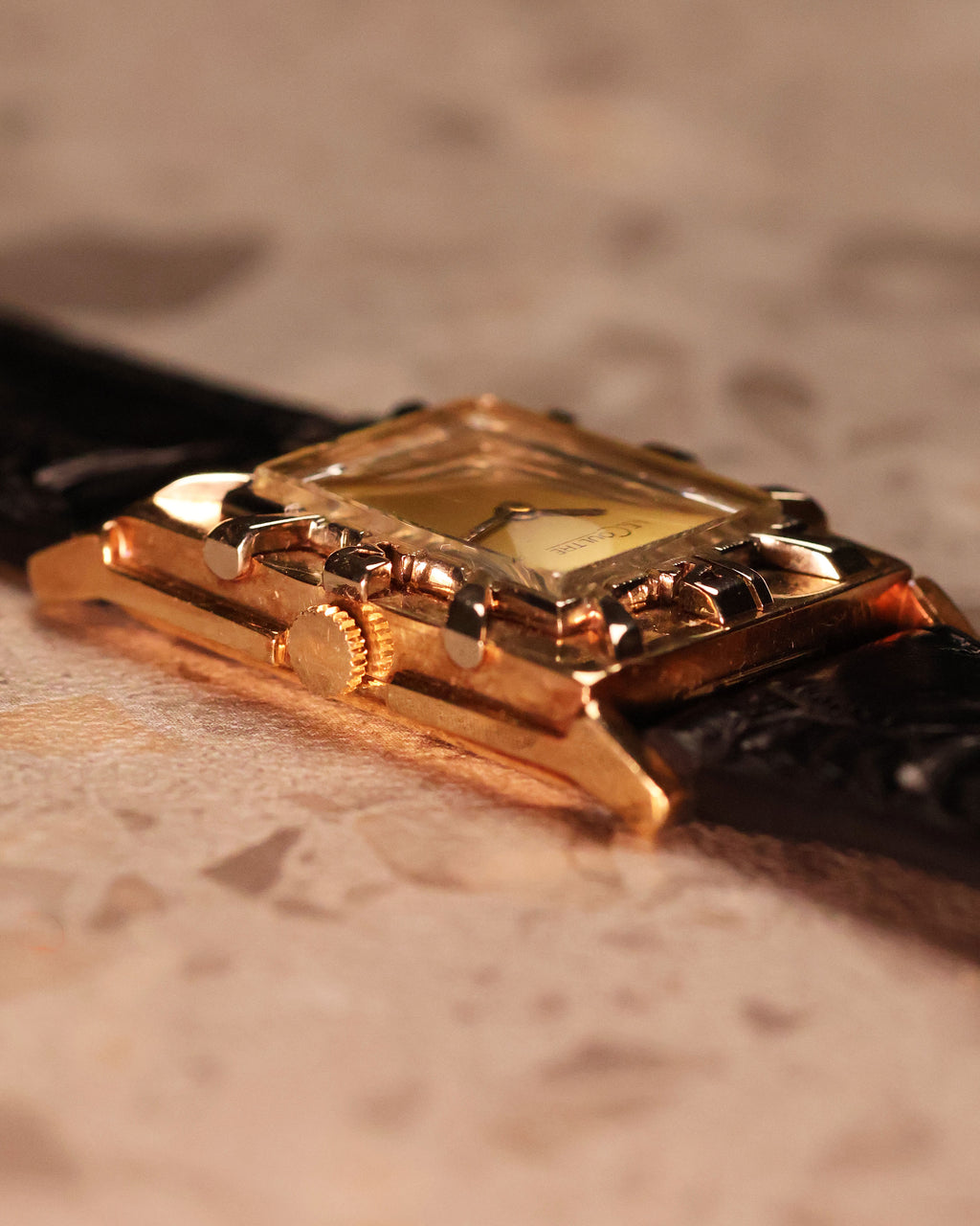 Angled close-up of the LeCoultre watch case showing the depth of the applied numerals on the gold bezel and smooth crystal curvature.