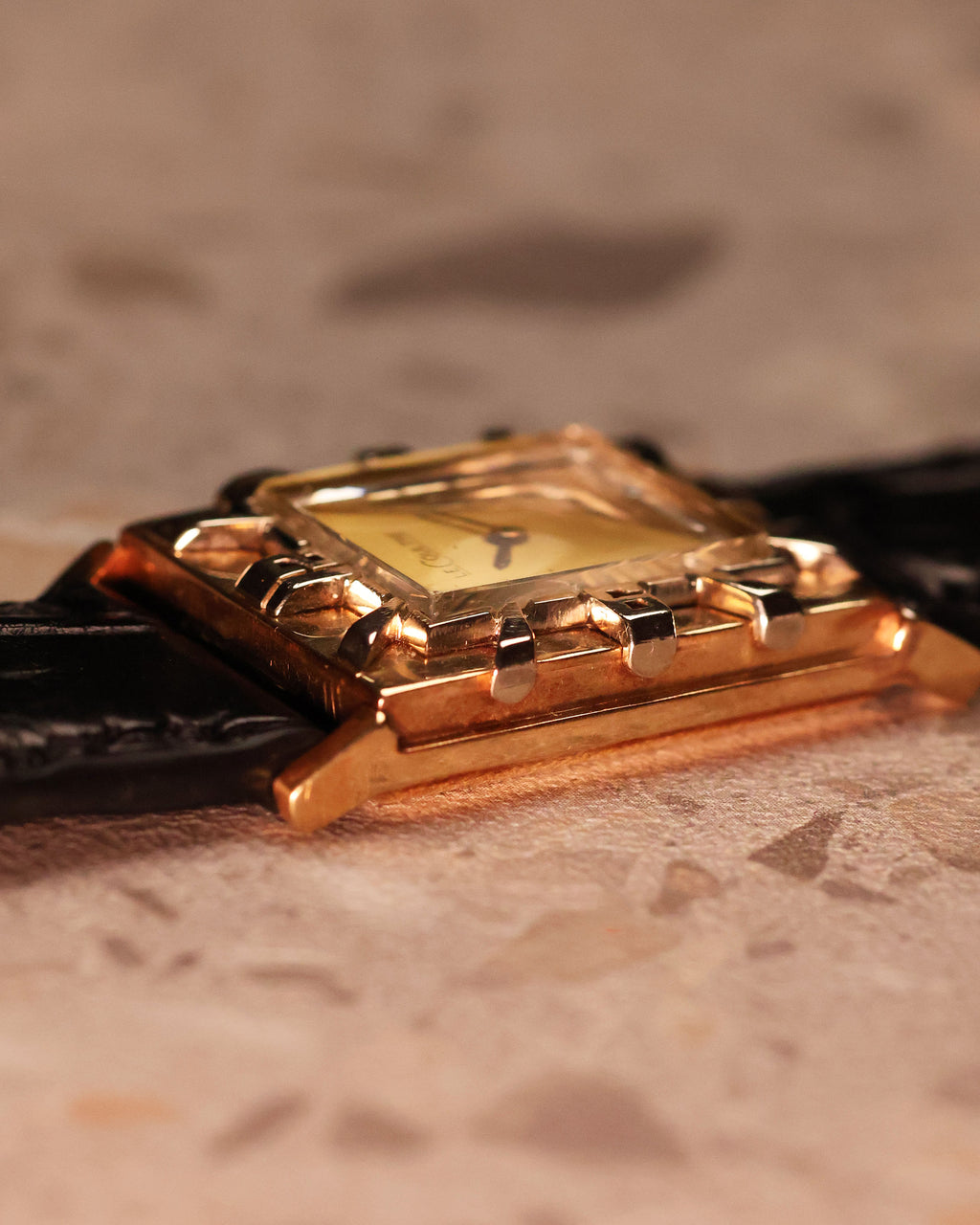 Low-angle side view of the LeCoultre Art Deco tank watch displaying its sculpted lugs and polished gold case.