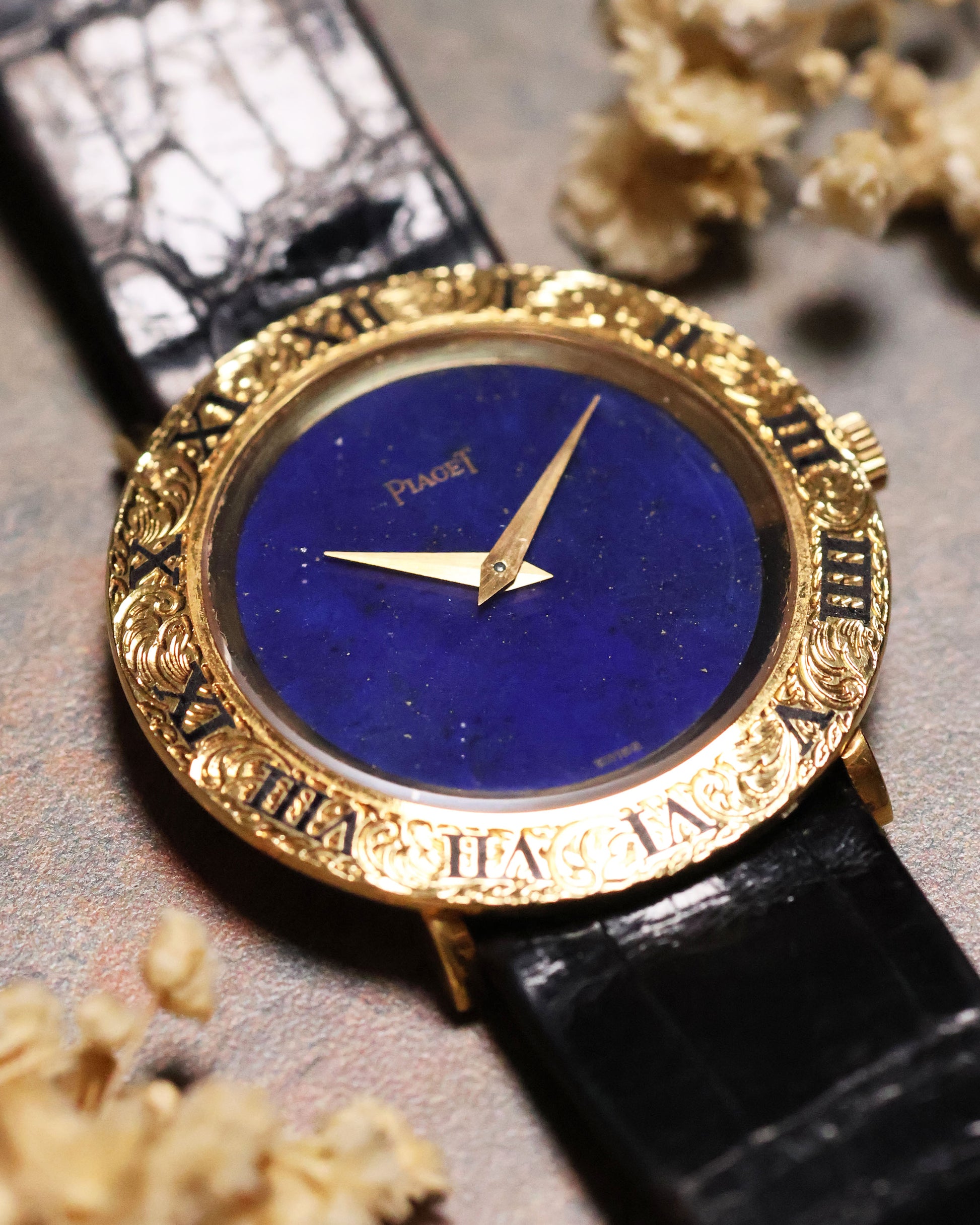 Angled view of the Piaget 9118 showing the vibrant lapis dial and intricately engraved gold bezel with Roman numerals, paired with a black leather strap.