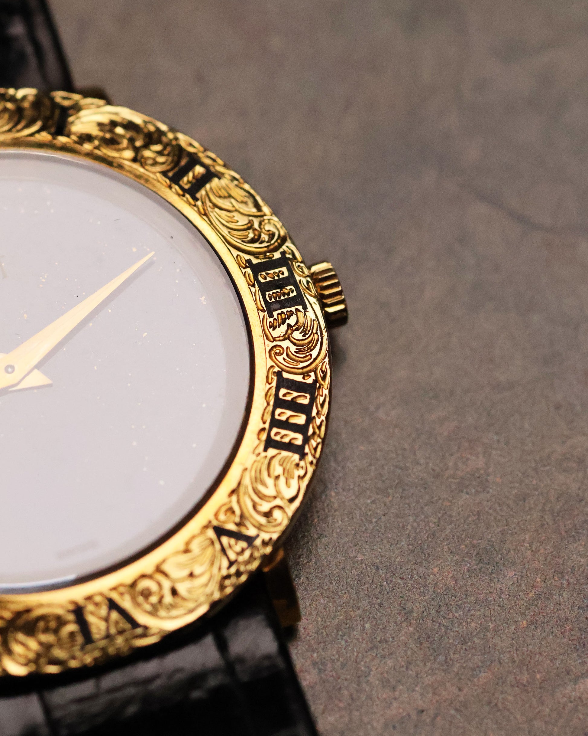 Macro detail of the Piaget 9118’s engraved gold bezel and crown, highlighting the carved Roman numerals and decorative scrollwork.