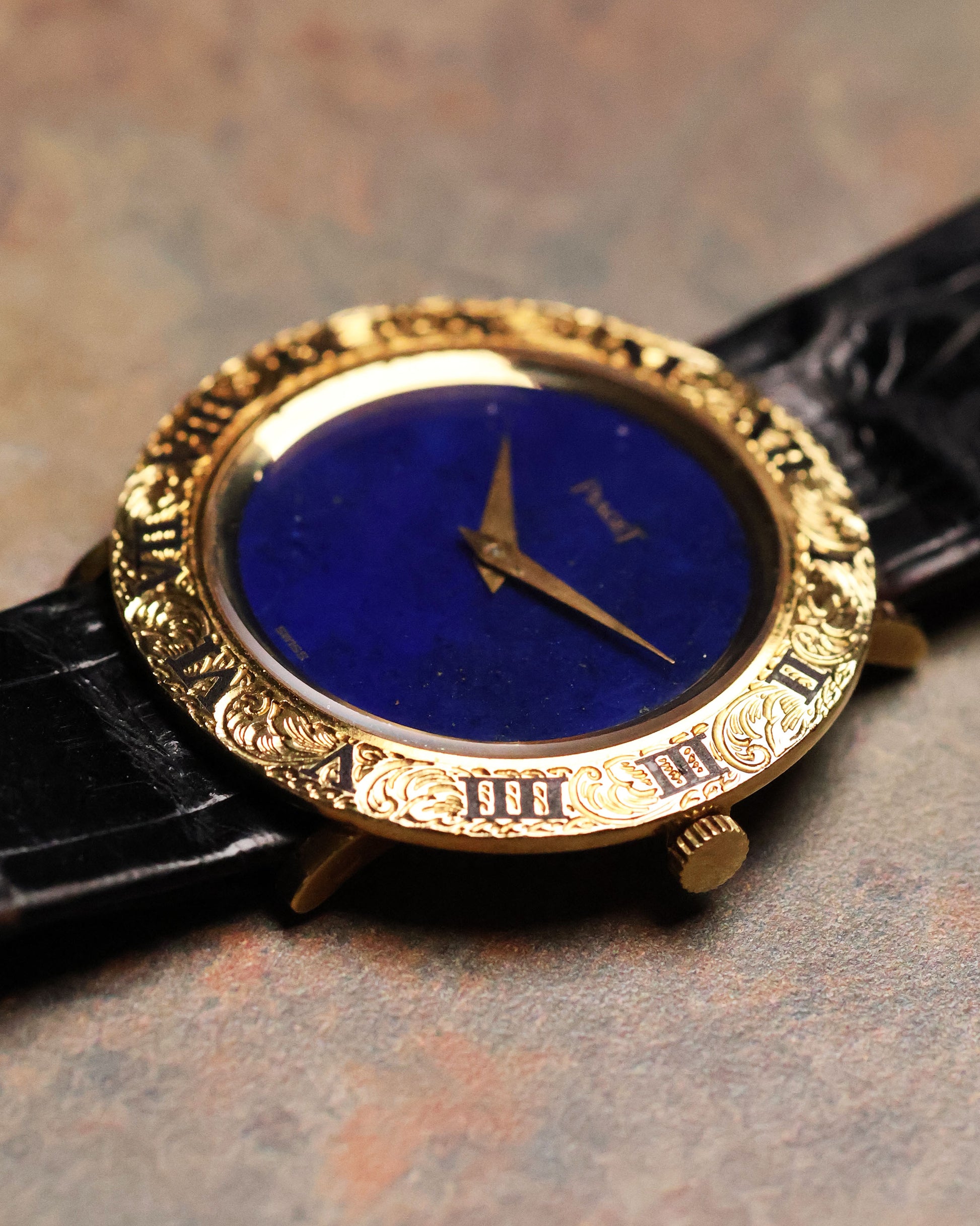 Low-angle shot of the Piaget 9118 showing the engraved Roman bezel and lapis stone dial, with the black leather strap partially visible.