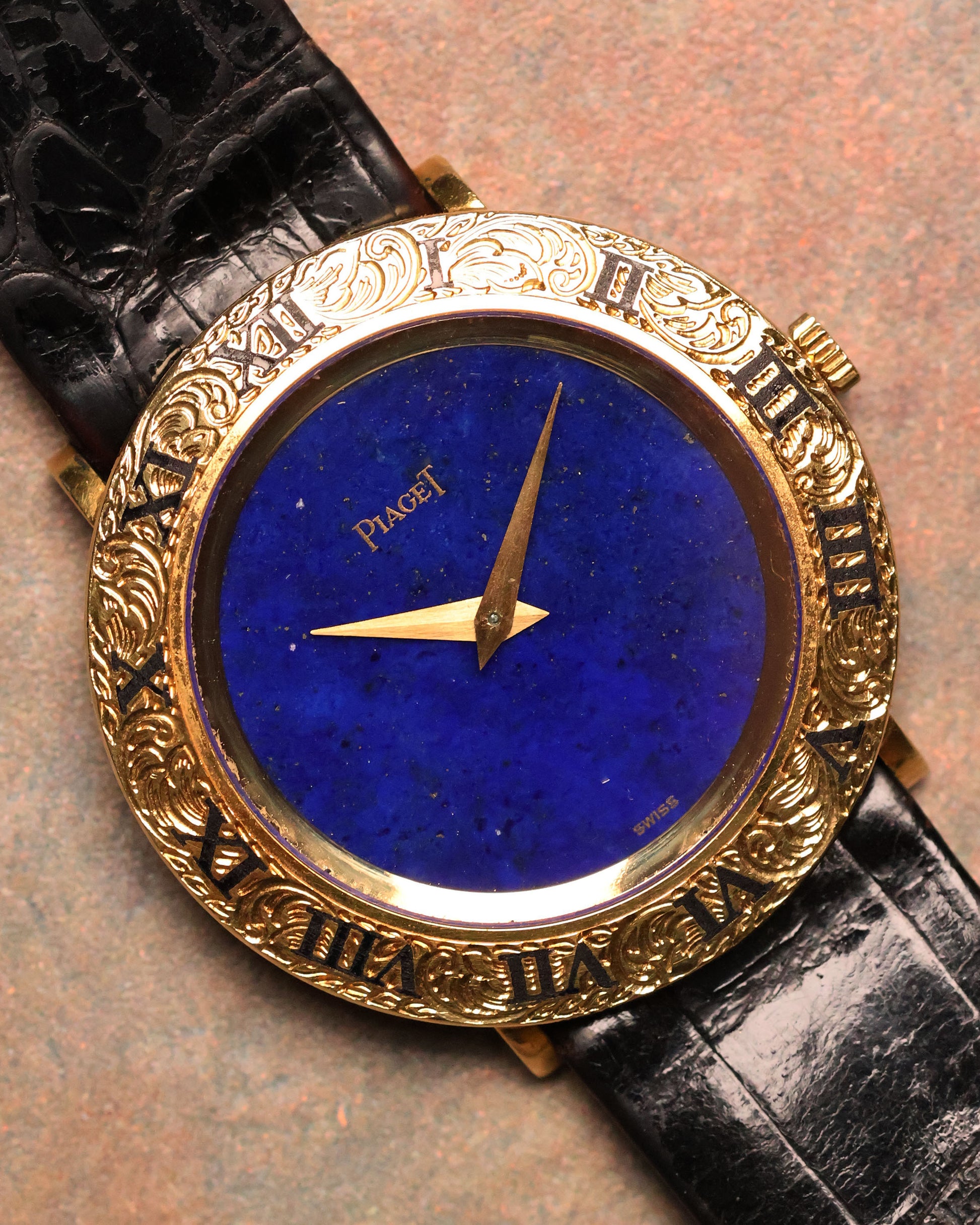 Straight-on shot of the Piaget 9118 featuring its deep lapis lazuli dial, engraved 18K gold Roman bezel, and gold hands on a black leather strap.