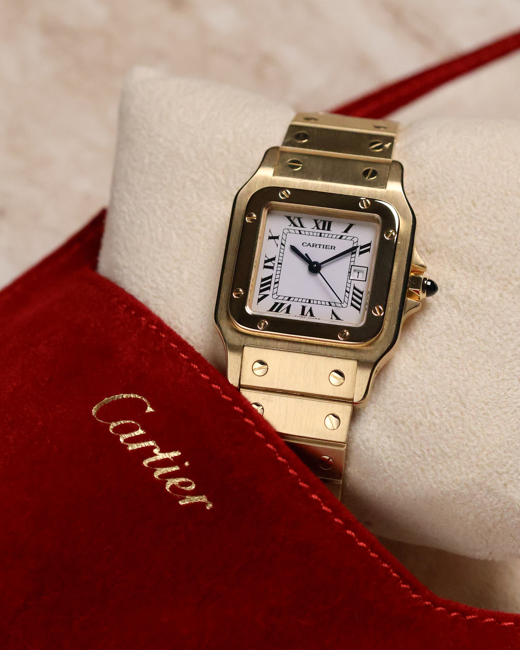 Cartier Santos Carrée Ref. 2960 photographed with the red Cartier suede pouch partially in frame, showing the square gold bezel, Roman dial, and screw-decorated bracelet.