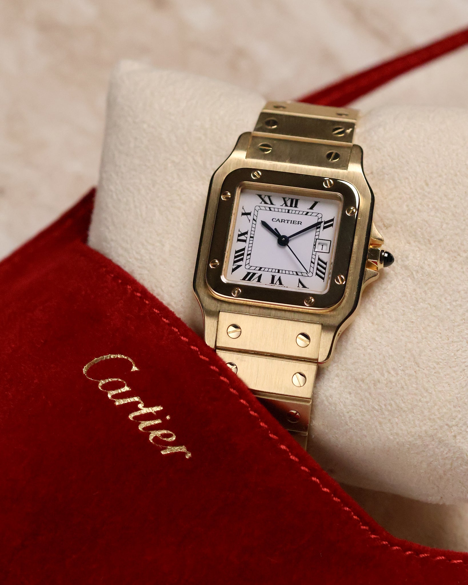 Cartier Santos Carrée Ref. 2960 photographed with the red Cartier suede pouch partially in frame, showing the square gold bezel, Roman dial, and screw-decorated bracelet.