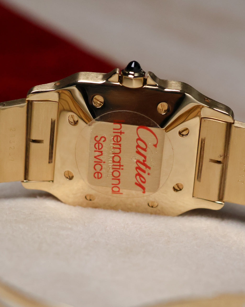 Caseback of the Cartier Santos Carrée Ref. 2960 showing the Cartier International Service sticker after recent servicing, with the gold case and bracelet partially visible.