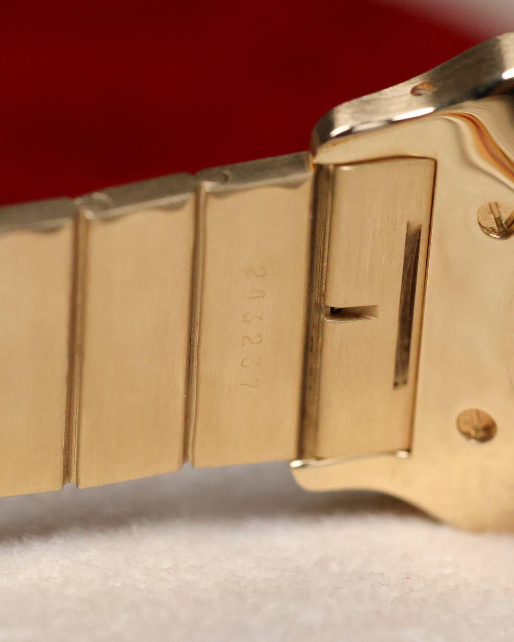 Close-up of the inner bracelet links near the clasp of the Cartier Santos Carrée, showing the engraved serial number on the 18K gold link.