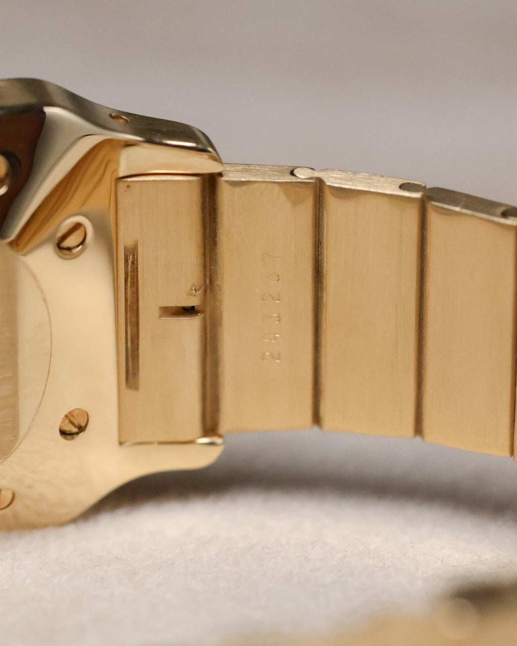 Detailed view of the serial engraving on the inside of the Cartier Santos Carrée bracelet link, emphasizing the crisp markings and brushed gold finish.