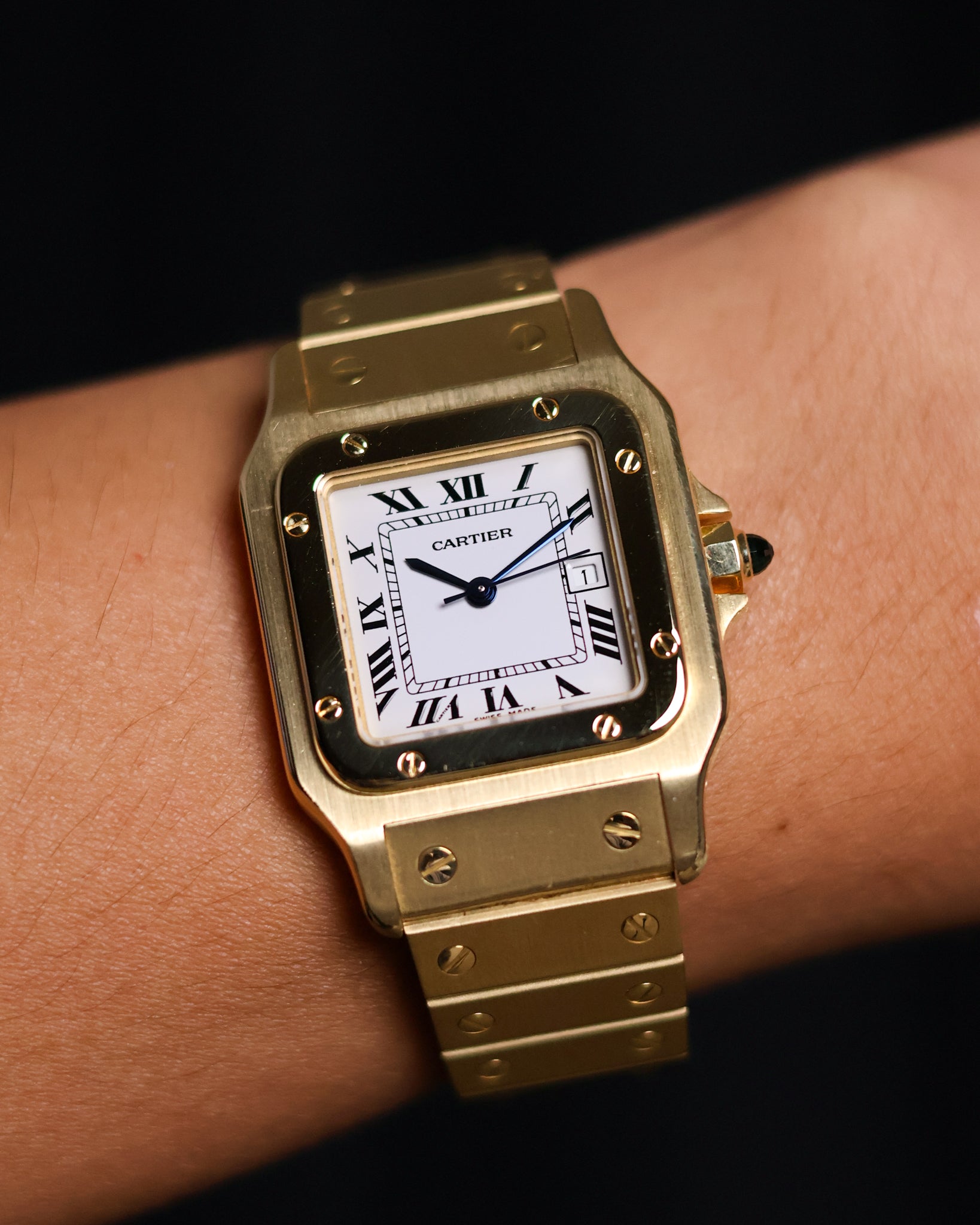 Wrist shot of the Cartier Santos Carrée Or Massif Ref. 2960 in solid 18K yellow gold, showing the watch worn on the wrist with the bright white Roman dial and blue cabochon crown.