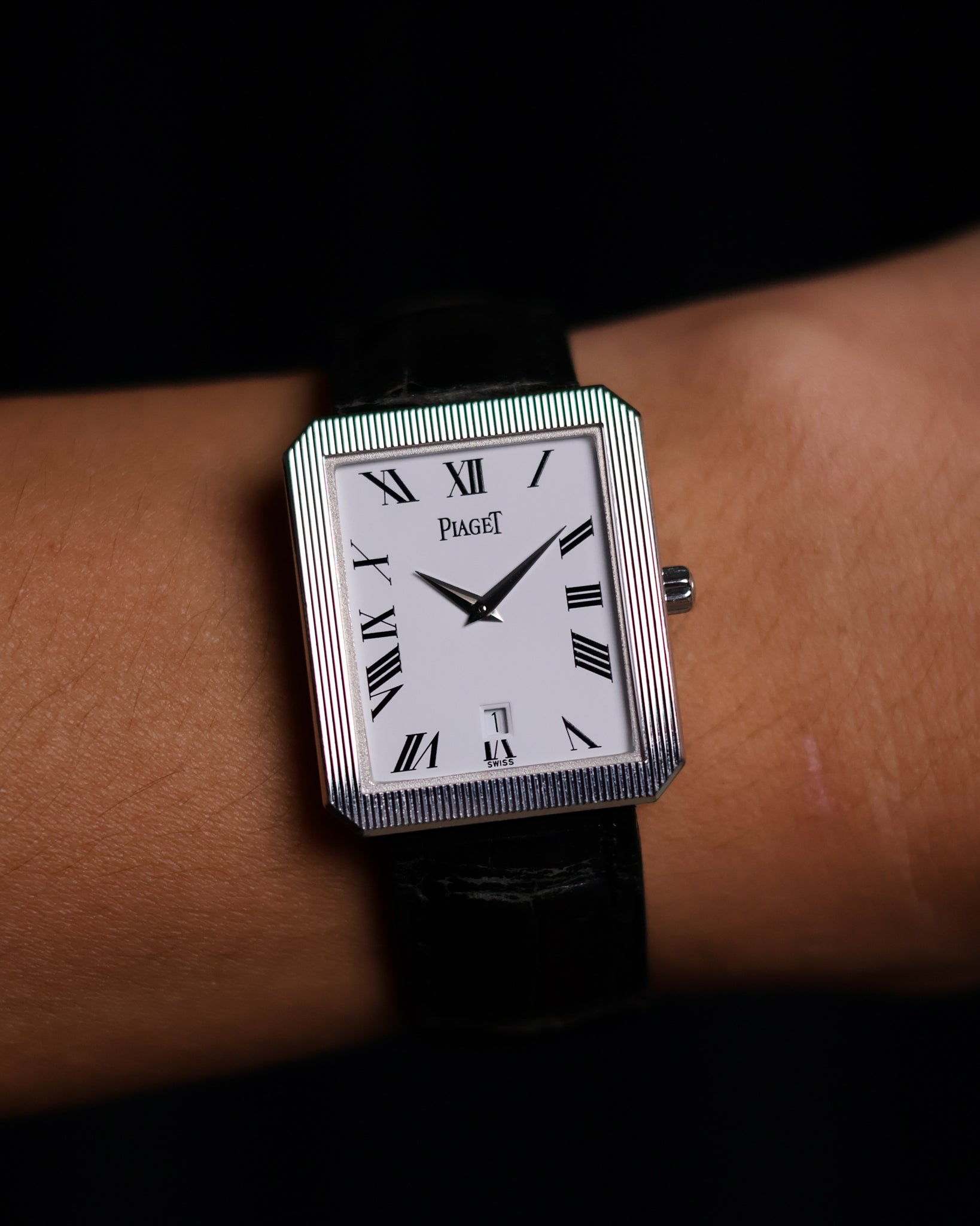 Close-up of Piaget Ref. 26354 dial featuring white background, black Roman numerals, and date window at 6 o’clock on a wrist.