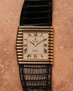 Front-facing top-down photograph of a Rolex Cellini Ref. 4015 featuring an ivory Roman numeral dial, asymmetric ribbed gold case, and black leather strap.