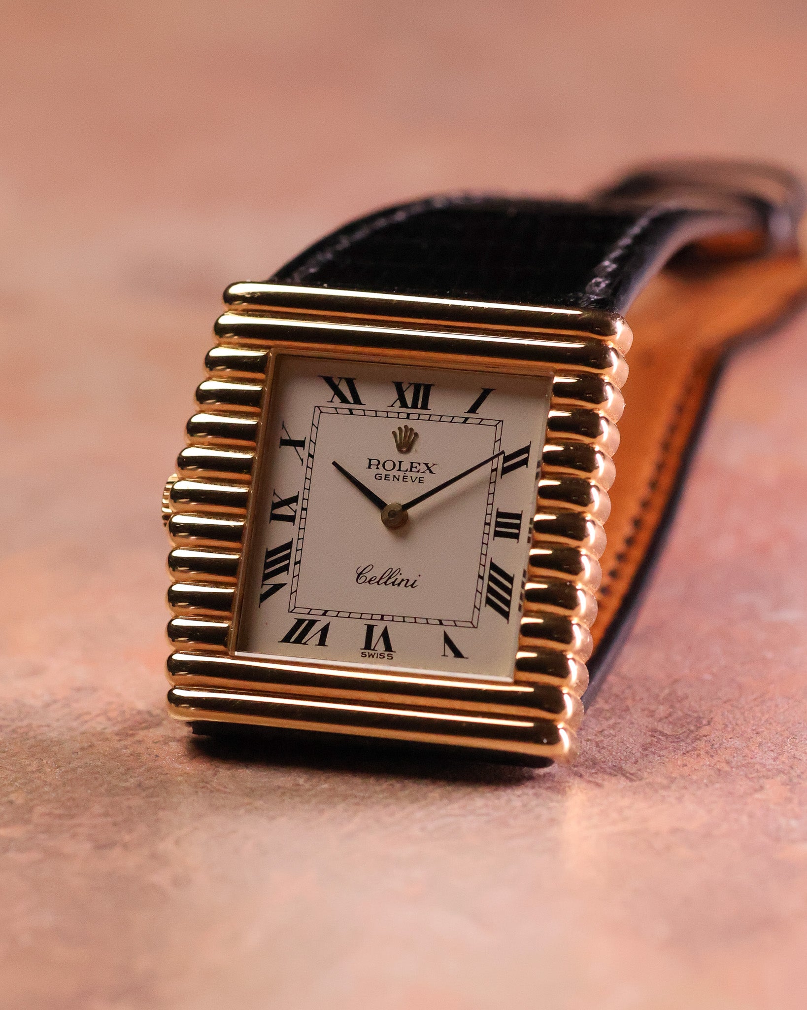 Upright angled view of the Rolex Cellini Ref. 4015 with its sculptural asymmetric gold case, Roman numeral dial, and black leather strap.