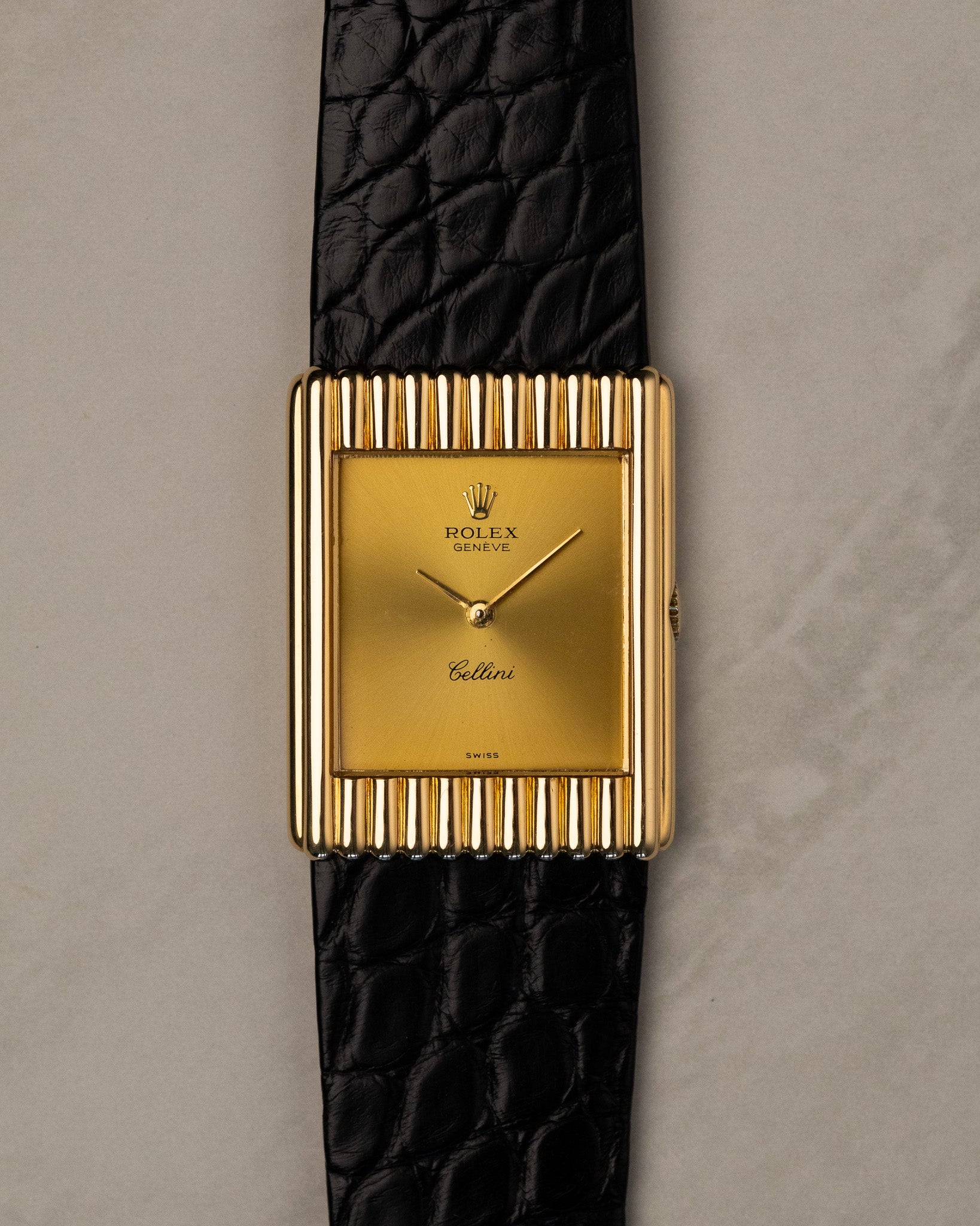 Straight-on front view of Rolex Cellini 4016 with gold dial, baton hands, and vertically fluted yellow gold case on black leather strap