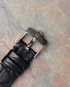 Original Rolex 18K white gold tang buckle with embossed crown logo attached to black leather strap.
