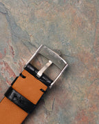 Reverse view of Rolex-signed white gold buckle marked “750,” mounted on black leather strap with tan lining.