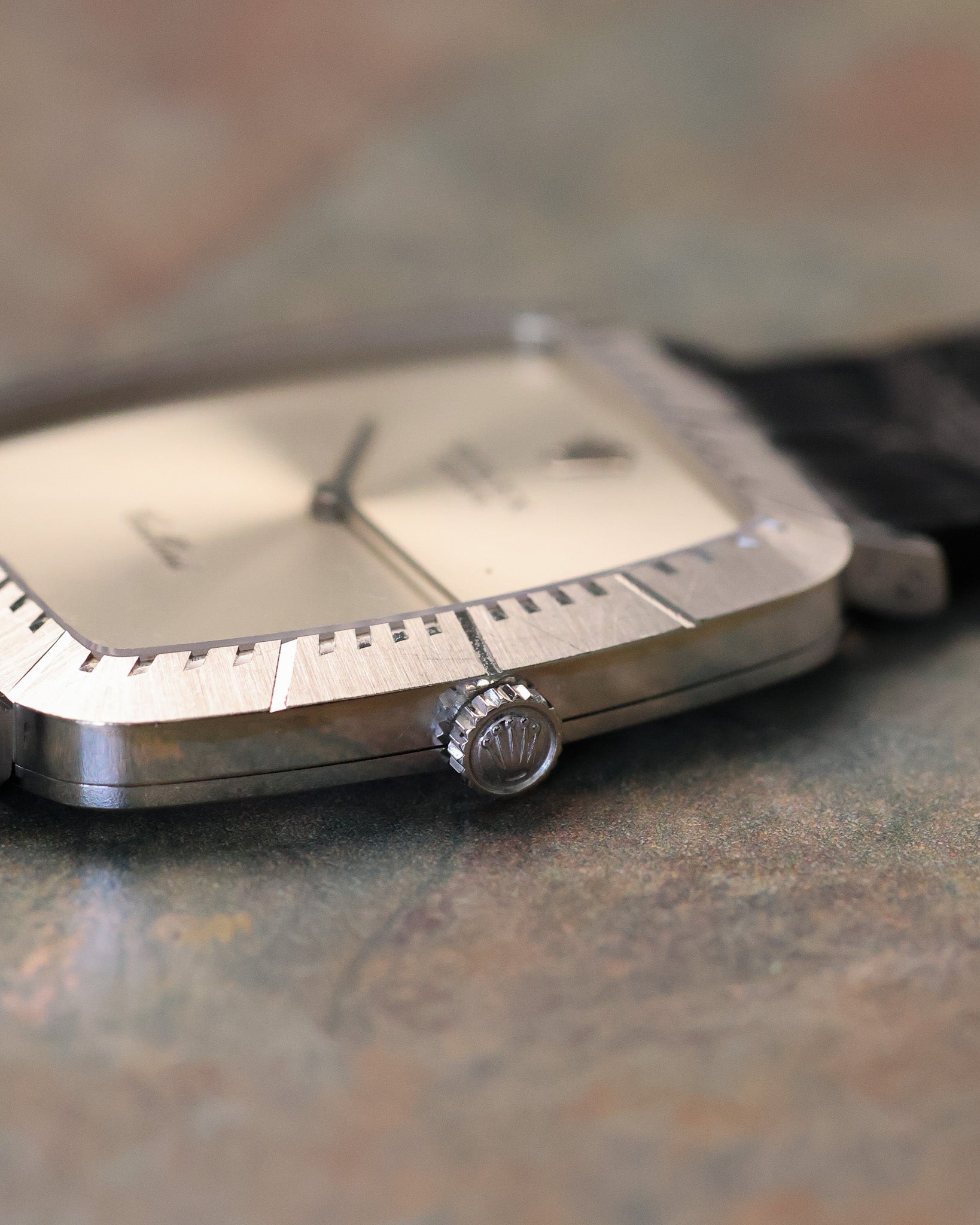 Macro side detail of Rolex Cellini crown with Rolex coronet engraving and fluted edge, set against brushed white gold case.