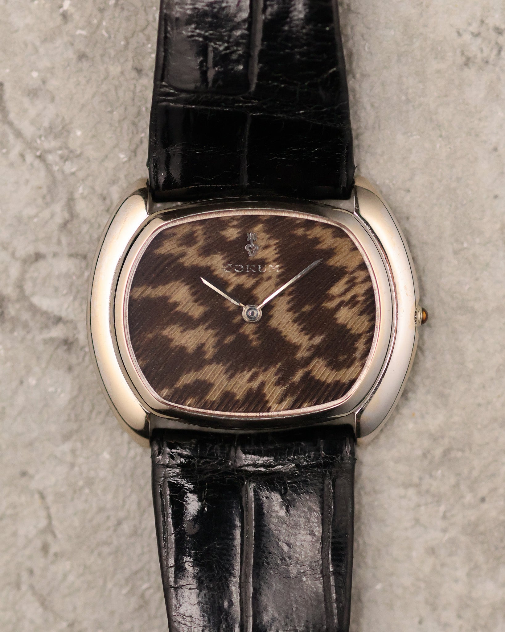 Close-up of Corum guinea fowl feather dial showing natural feather pattern and minimalist two-hand layout.
