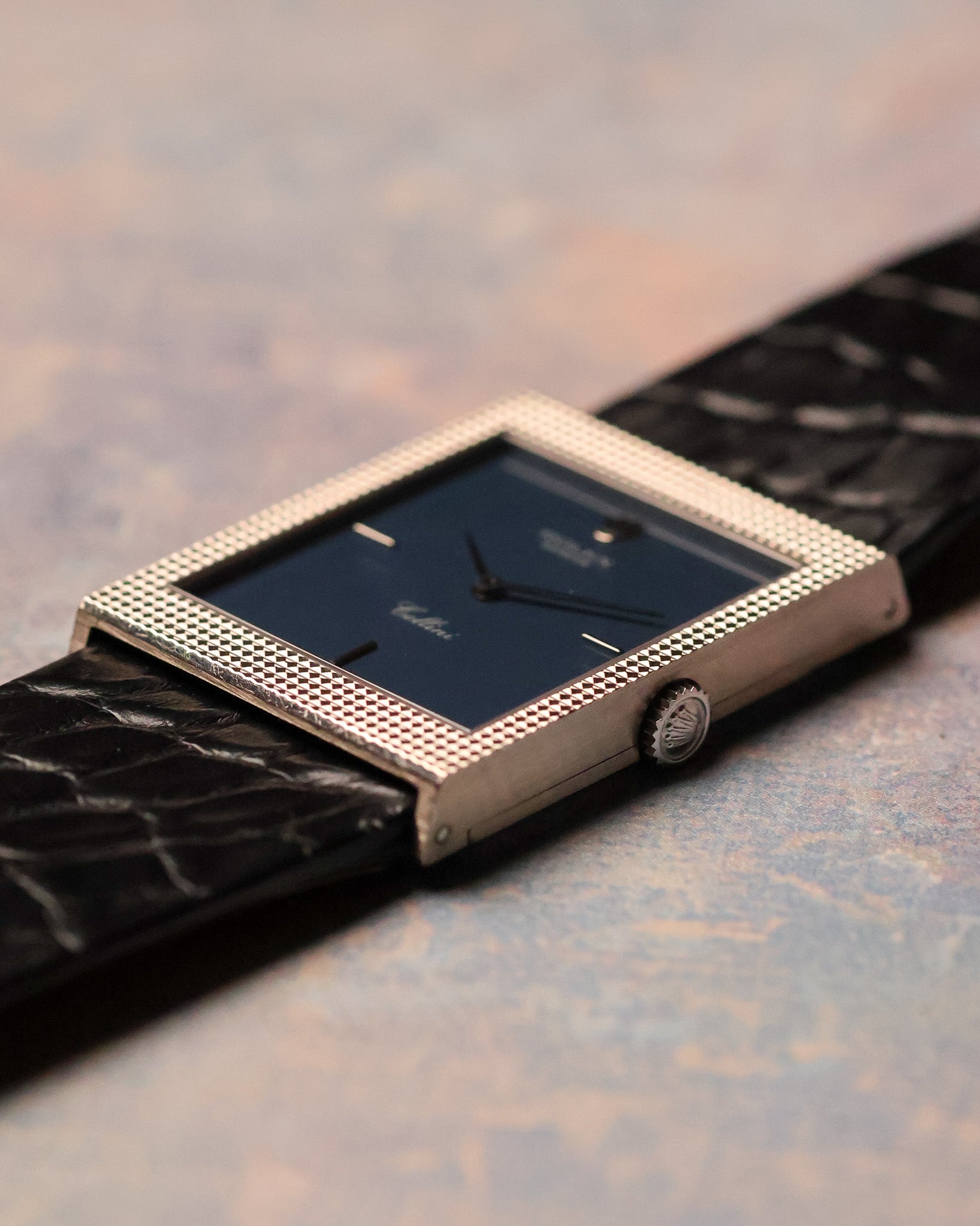 Angled wrist-level view emphasizing the depth and sharpness of the hobnail engraved white gold case and matte blue dial.