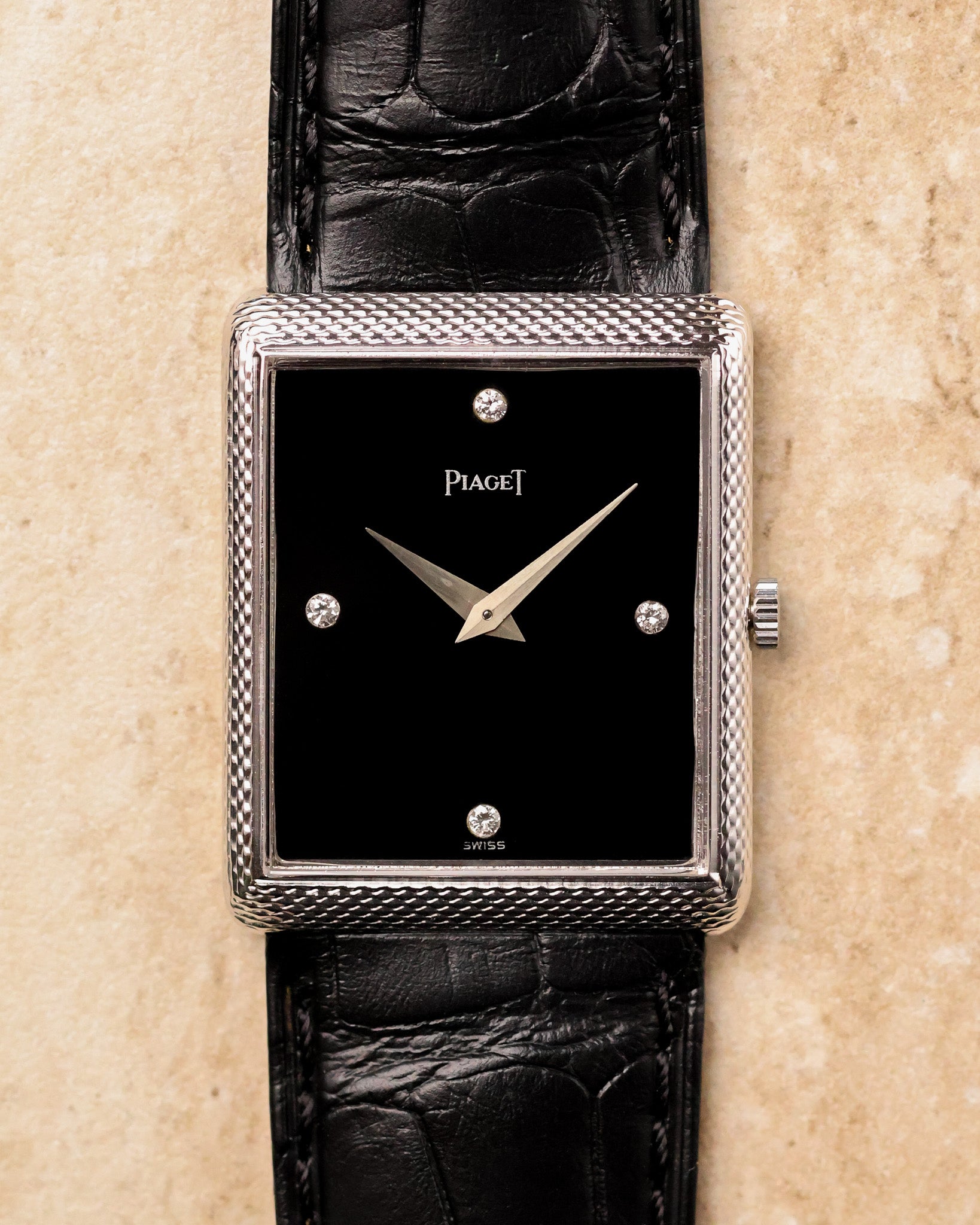 Front view of Piaget 9152 showing rectangular woven white gold case, glossy black onyx dial and four diamond hour markers.