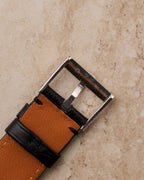 Reverse view of Piaget buckle stamped “750 SWISS,” mounted on black leather strap with tan lining.