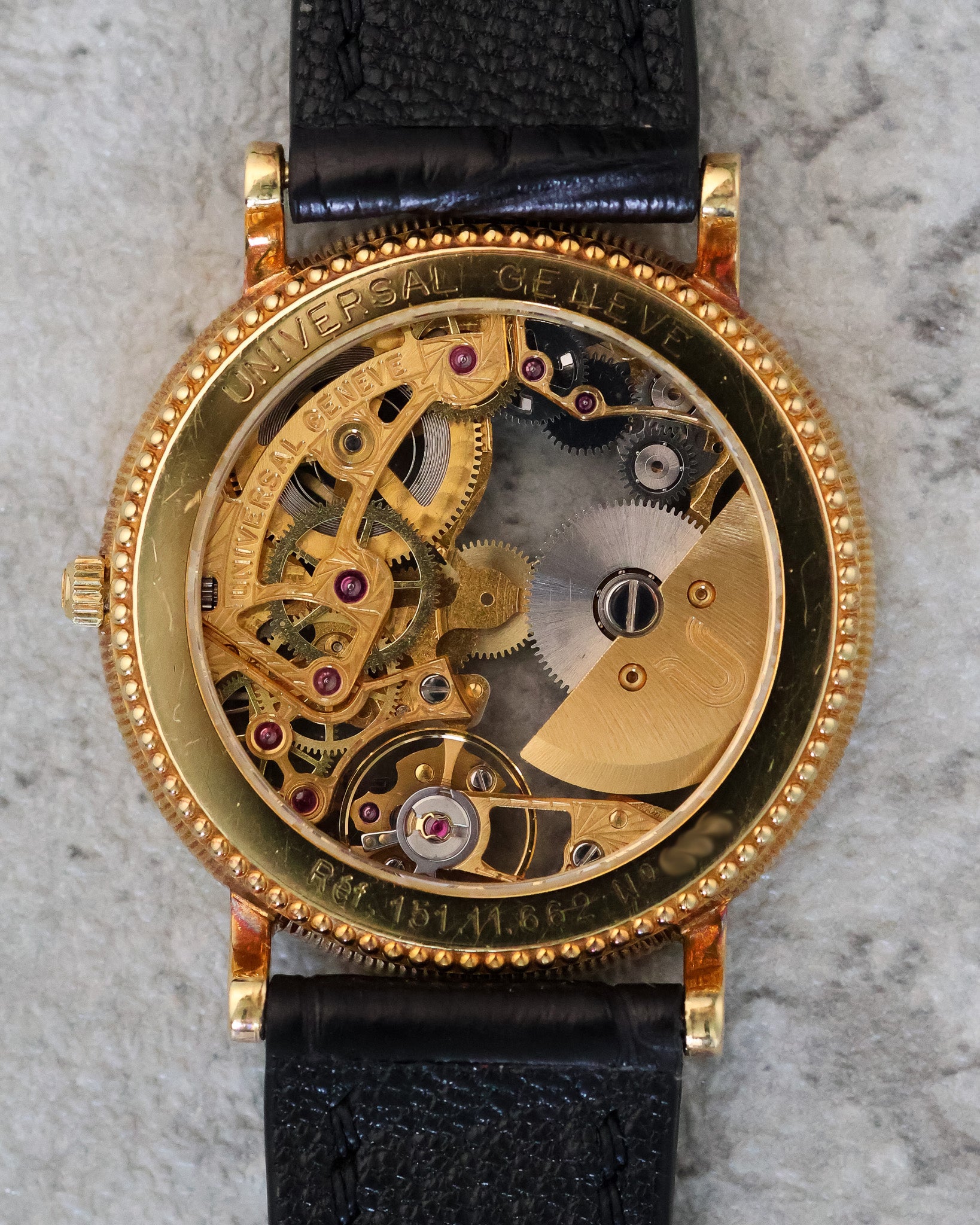 Universal Genève skeleton watch caseback showing the automatic micro-rotor movement in 18K yellow gold, with engraved brand markings and coin-edge case detailing.
