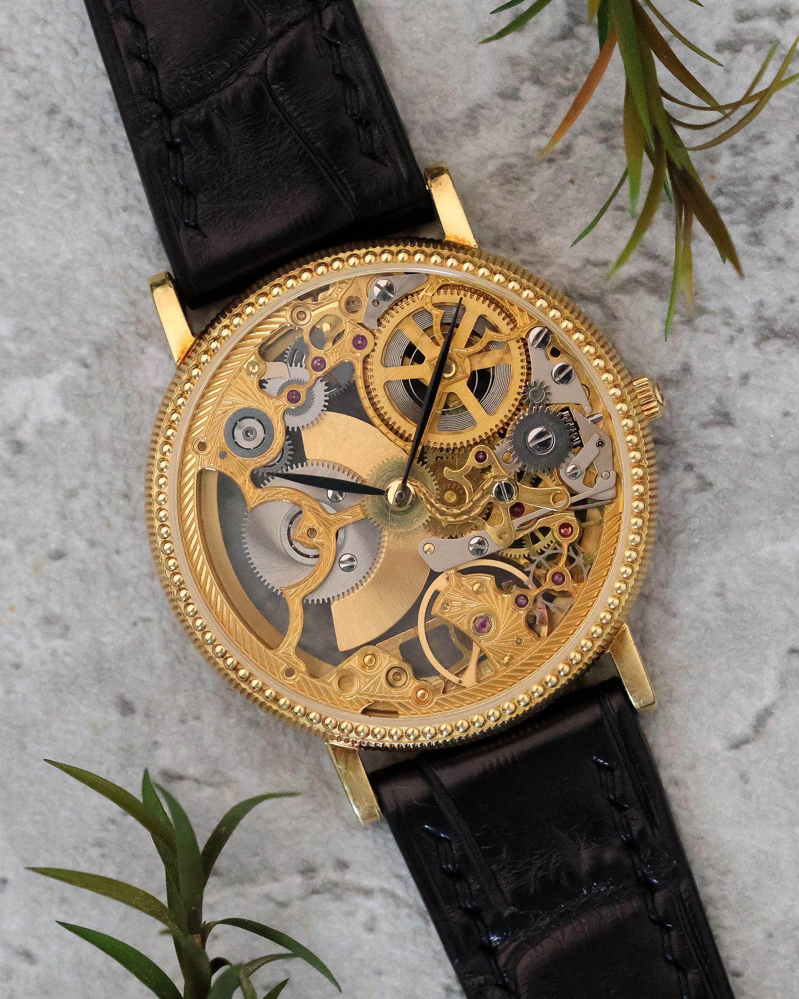 Front view of the Universal Genève skeleton watch, highlighting the openworked dial, exposed gears, and finely engraved gold bridges within a coin-edge yellow gold case.