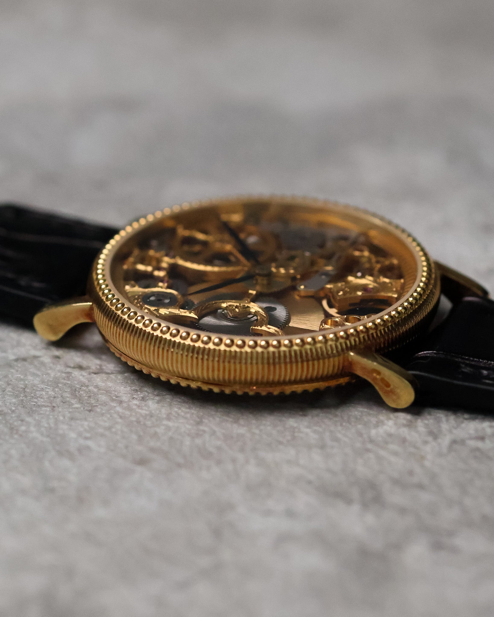 Low side profile of the 18K yellow gold case, emphasising the coin-edge bezel, slim case height, and curved lugs.