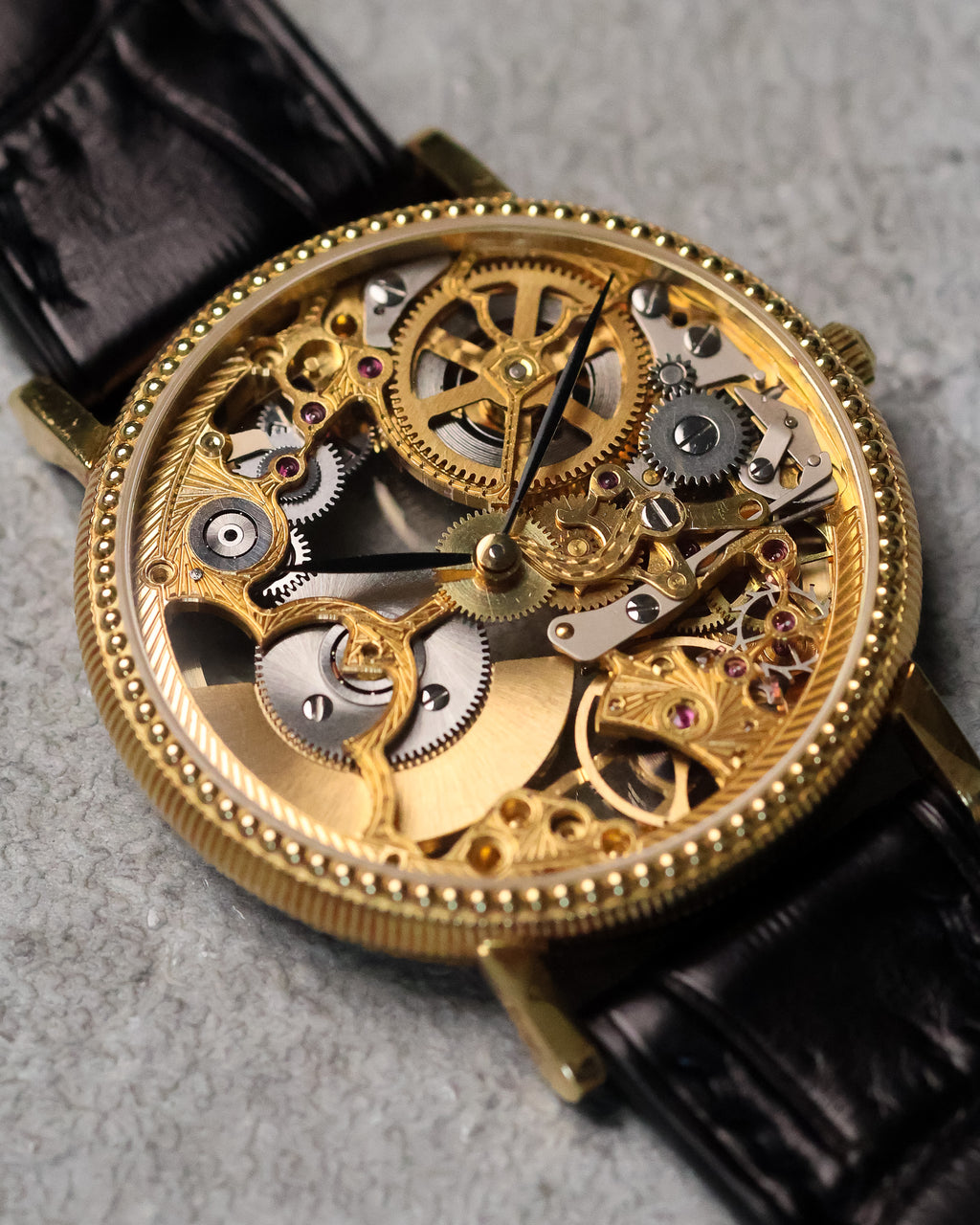 Angled close-up of the skeletonised dial, revealing the balance assembly, gear train, and contrasting gold and steel components.