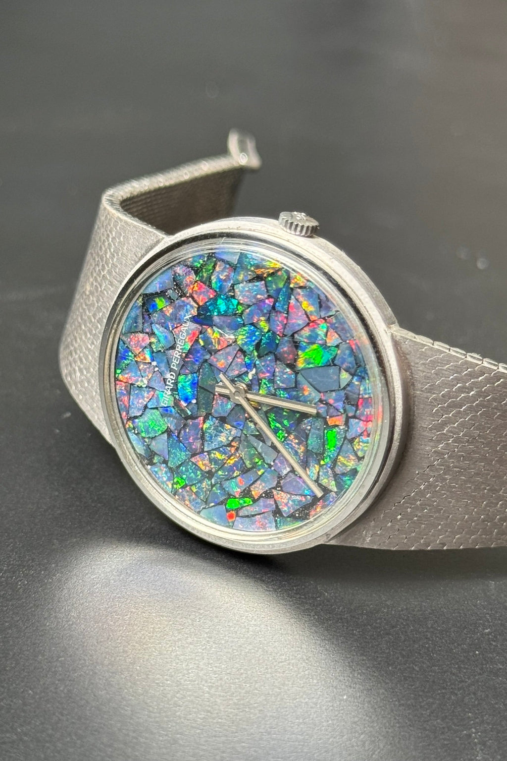 Close-up of Girard-Perregaux opal dial displaying iridescent hues of blue, green, and red under acrylic crystal