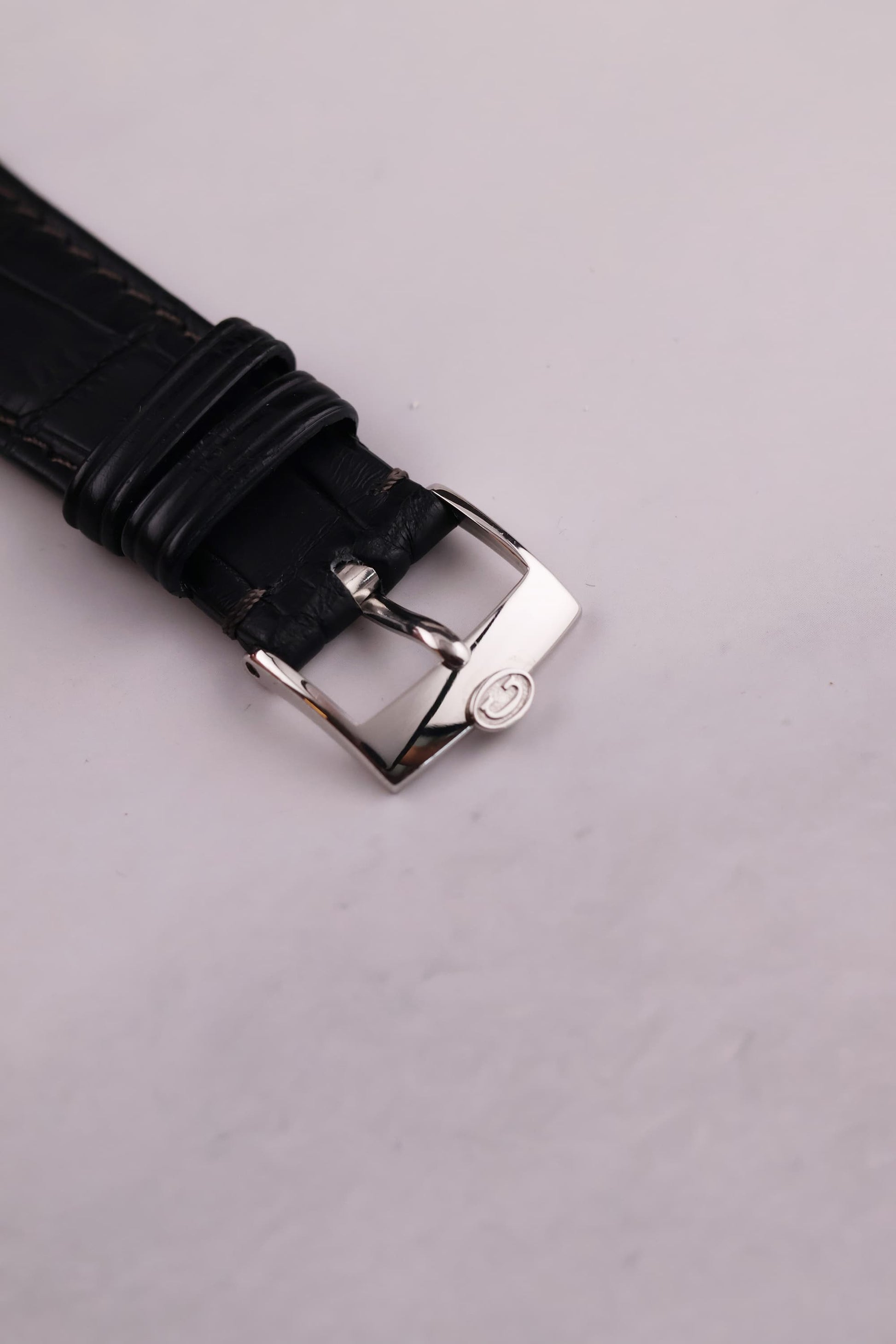 Close-up of the black alligator leather strap and polished buckle, complementing the minimalist aesthetic of the watch.